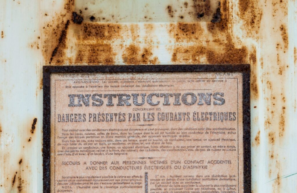 图片 8：一张海报，上面用粗体字写着“说明”。海报安装在一个生锈的金属结构上。